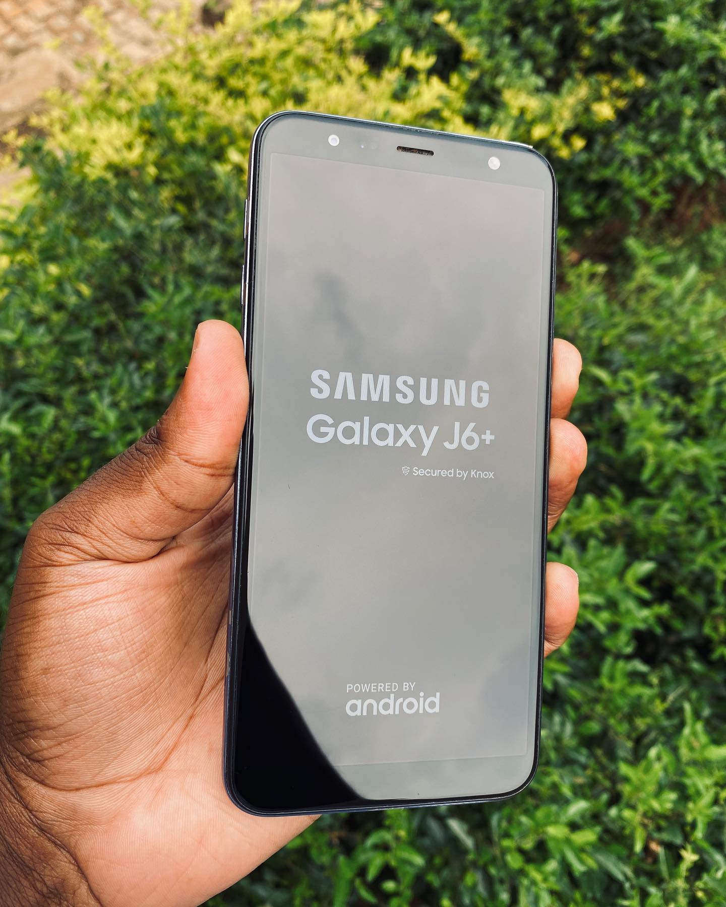 A budget Android smartphone held in one hand, showing the glossy screen and modern look of 2026 mid-range models